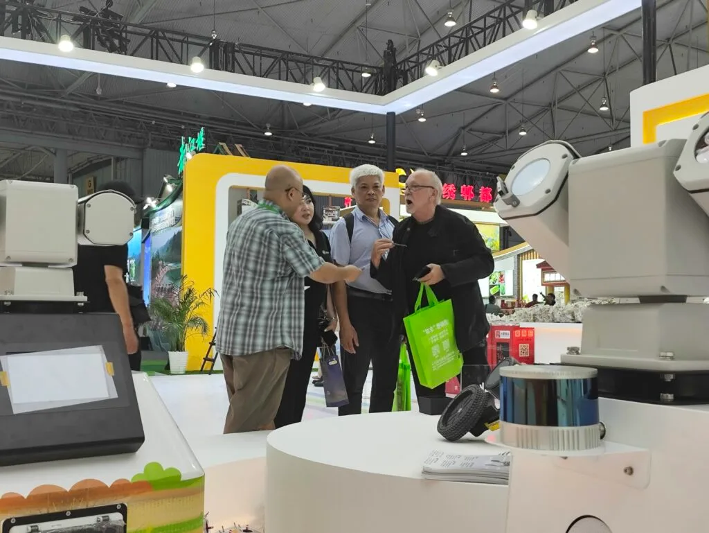 GC AGV&AMR Robotics representatives meeting international customers and discussing warehouse automation technologies at an industry exhibition.